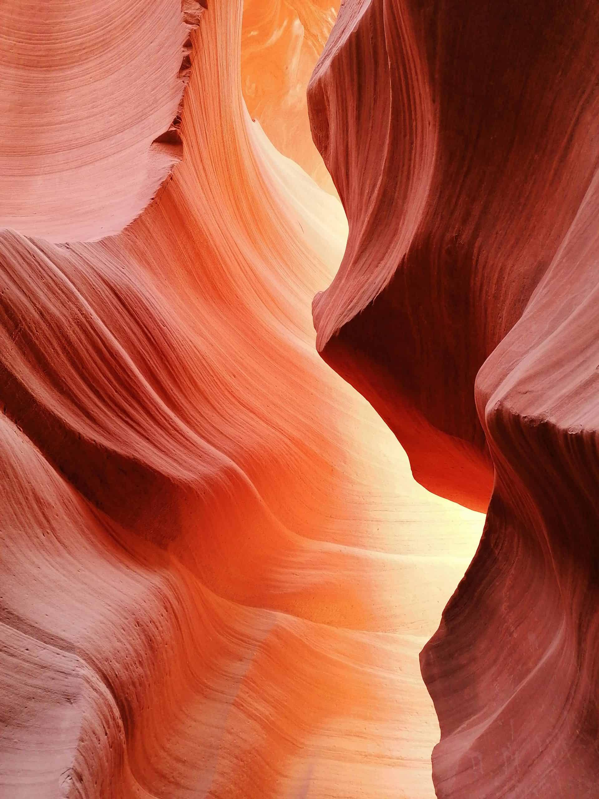 21b Consulting - A stunning view of Antelope Canyon, featuring smooth, reddish-orange sandstone walls with intricate, flowing patterns. Light filters through from above, illuminating the narrow, winding passage and highlighting the natural curves and textures of the rock formations.